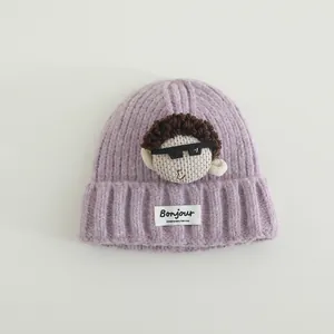 Dettaglio cappello a maglia viola chiaro per bambini con bambola 3D ed etichetta Bonjour