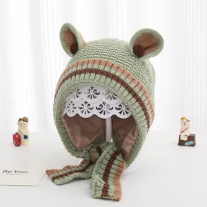 Dettaglio del cappello in maglia verde per neonati con orecchie, fodera e lacci a righe