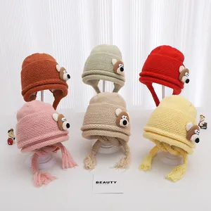 Close-up of knit baby beanies with cute bear ears and braided tassels in six soft colors