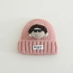 Dettaglio del berretto in maglia rosa per bambini con patch bambola e etichetta Bonjour