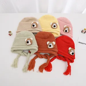 Detail of knitted baby beanies with cute bear patches in six vibrant warm colors