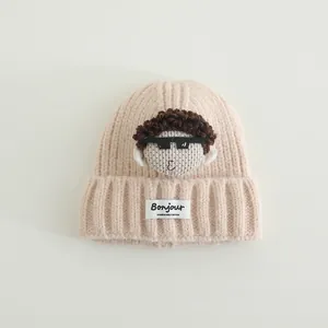 Dettaglio del cappello in maglia per neonati con bambola cartoon ed etichetta Bonjour