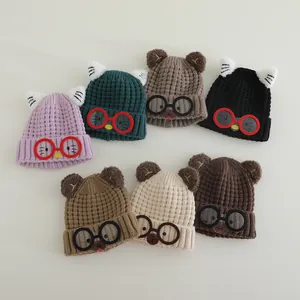 Detail of knitted children's winter hats featuring cute animal ears and glasses decor