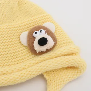 Bright yellow knitted baby beanie featuring a cute 3D brown bear patch for winter