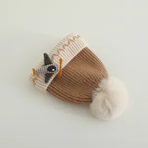 Detail van de gebreide babymuts met cartoon vliegtuigpatch en een zachte pluizige pompon