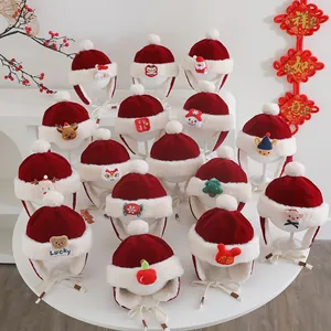 Close-up of festive red velvet baby winter earflap hats with white faux fur and pom-poms