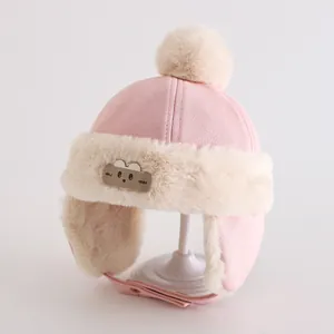 Detail van roze trapperhoed voor kinderen met schattige berenpatch en zachte pluche pompons
