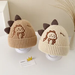 Detail of knit baby hats featuring cartoon dinosaur embroidery and 3D decorative scales