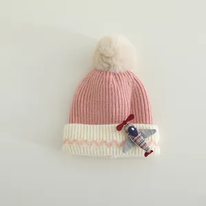 Detail van de gebreide textuur van een roze baby wintermuts met schattige vliegtuig