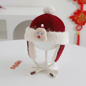 Detail of red velvet baby winter hat with fur trim, deer doll and pom pom on a stand