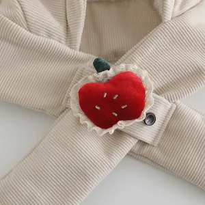 Detail of beige corduroy hat featuring a 3D red strawberry plush and brown button