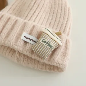 Beige knitted beanie for kids with coffee cup patch and warm ribbed edge detail