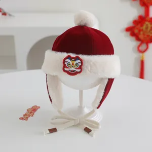 Detail of red winter baby earflap hat with traditional lion embroidery and white fur trim