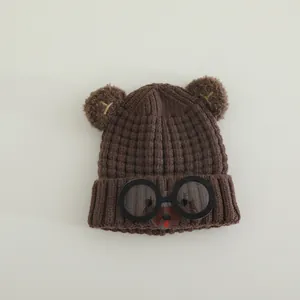 Detailed close-up of brown knit hat with cute bear ears and round glasses decoration