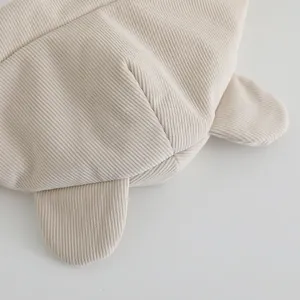 Detail of baby winter hat featuring soft beige corduroy fabric and cute animal ears