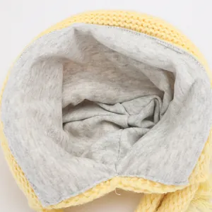 Close-up of winter knit hat showing yellow yarn texture and grey warm lining fabric