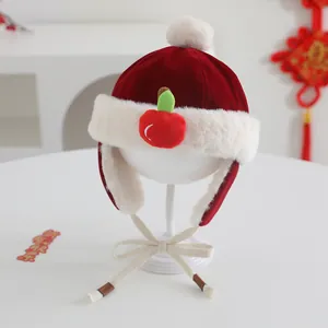 Close-up of red festive baby winter hat with plush white fur and cute apple detail