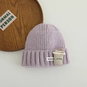 Detail shot of lilac knitted kids hat with 3D coffee cup patch and Honey Bea woven label