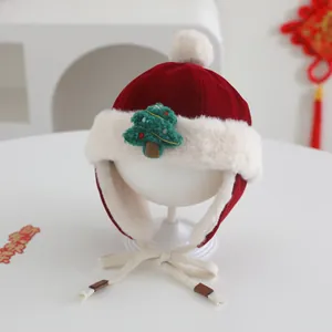 Close-up of a red festive baby earflap hat with white faux fur and Christmas tree patch