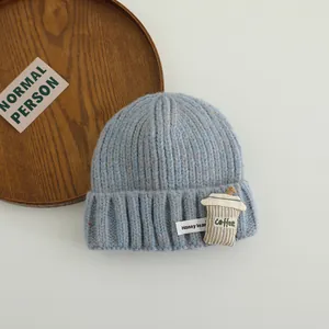 Detail of light blue knit hat with coffee cup patch and Honey bear label on wood tray