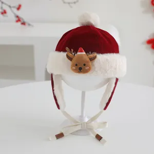 Detailed view of red velvet baby Christmas hat with plush fur balls and reindeer embroidery