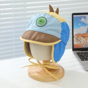 Detail der Plüschinnenseite und Dino-Aufnäher an blau-gelber Kinder-Fliegermütze