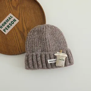 Close-up of knit winter hat featuring a coffee cup patch and Honey bear label