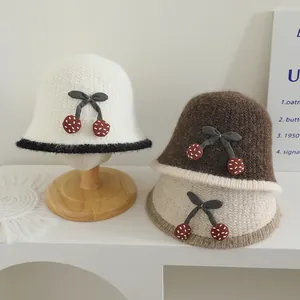 Détail de chapeau cloche en tricot pour enfants avec décor cerise et nœud papillon