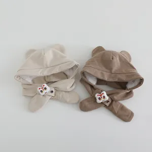 Detail of baby winter earflap hats in beige and brown featuring cartoon lion embroidery