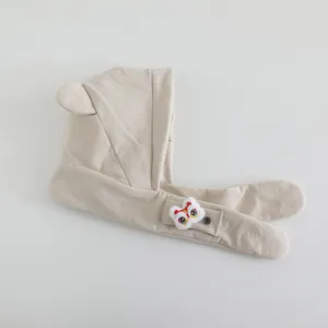 Detail of warm beige corduroy kid's earflap hat with cute lion dance pendant and ears