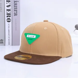 Detalle de la gorra plana de lona caqui con un parche triangular verde decorativo