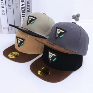 Detalle de gorras de béisbol bicolor con parches triangulares y pegatinas doradas en visera