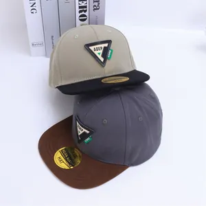 Detalle de gorras de béisbol de visera plana bicolor con parche triangular bordado