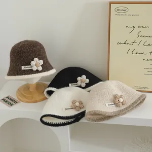 Détail de bobs en maille en quatre couleurs avec patchs floraux et bordure contrastée
