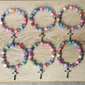 Set of six colorful polymer clay bead bracelets with cross pendants on wood background