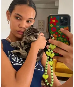 Detail of green heart beaded phone strap on floral case shown in lifestyle use