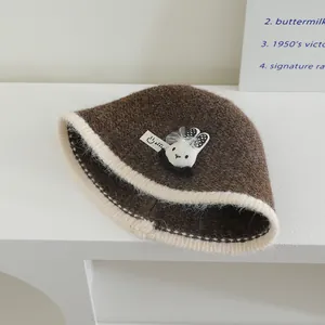 Détail d'un chapeau tricoté avec lapin en peluche, nœud en résille et bord contrasté