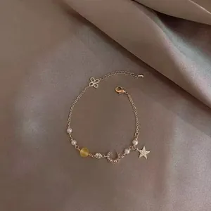 Détail des breloques étoile et lune avec perles sur un bracelet en or rose élégant