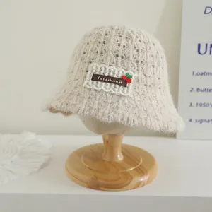 Chapeau cloche tricoté pour enfants couleur avoine avec écusson cerise sur support