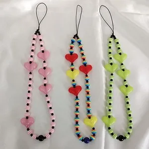 Three beaded phone charms with heart accents on white silk, showing craftsmanship and colors