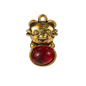Detail of a tiger pendant with antique gold finish and oval red stone inlay