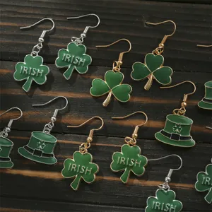 Green St. Patrick's Day shamrock and leprechaun hat earrings on a rustic wood background