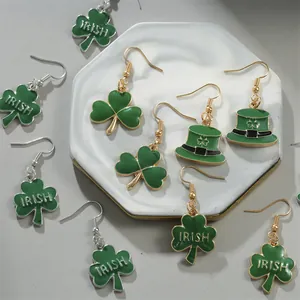 Detail of green shamrock and Irish hat alloy earrings on a marble display tray