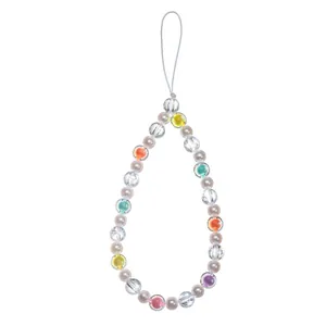 Detail of colorful bohemian beaded phone charm with heart shapes and pearls on white