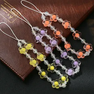 Bunte Handyketten aus Resin mit Blumenperlen und transparenten Herzen auf Lederhintergrund