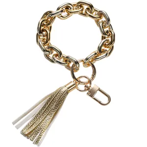 Detailed macro view of a chunky gold metal chain keychain with a stylish leather tassel