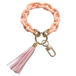 Close-up of pink acrylic chain bracelet keychain with leather tassel and gold hardware