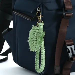 Handmade green cotton macrame leaf keychain with fringe tassel on a blue backpack zipper
