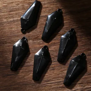 Détail de six breloques cercueils noirs en alliage avec anneaux sur fond bois sombre
