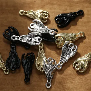 Three colors of bat shape alloy metal charms for DIY jewelry making on leather background